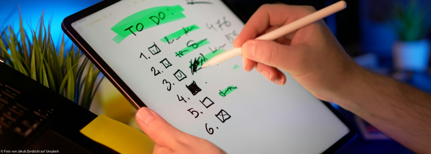 Person, die den Stift auf dem Tablet verwendet, um die To-Do-Liste abzuhaken.