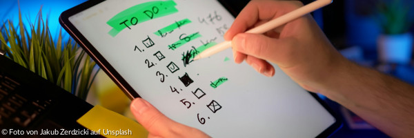 Person, die den Stift auf dem Tablet verwendet, um die To-Do-Liste abzuhaken.